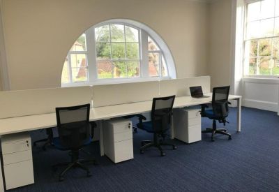 Open-plan office with white desks, black chairs, and a large arched window.