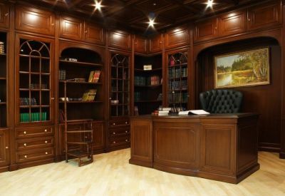 Traditional executive office featuring dark wood paneled walls, floor-to-ceiling bookshelves, and a leather chair.