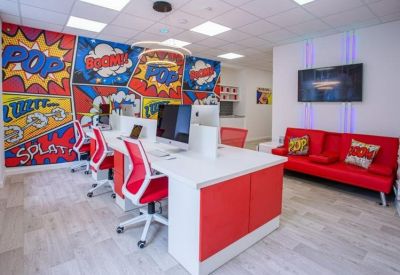 Modern open-plan office with red chairs and a vibrant comic book style wall mural.