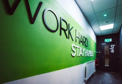 Corridor featuring a bright green wall with the motivational slogan Work Hard Stay Humble.