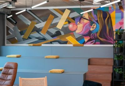 Lounge area with tiered blue seating, a colorful mural, and mid-century modern armchairs.