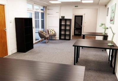 Spacious coworking area with wooden desks, storage units, and comfortable armchairs.