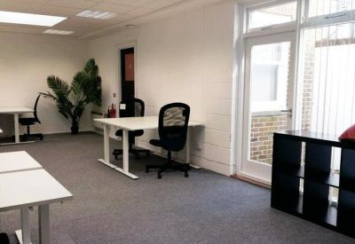 Bright open-plan office with white desks, black chairs, and a large window.