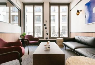 Intimate lounge area with plush armchairs and a leather sofa near tall windows.