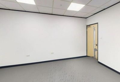Spacious empty office room with white walls and grey carpeting.