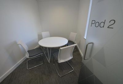 Small private meeting pod with a round white table and four chairs.