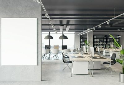 Bright workspace with long white desks, ergonomic chairs, and a large blank wall canvas.