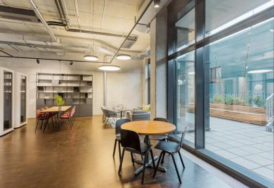 Spacious communal dining area with round wooden tables and large floor-to-ceiling windows.