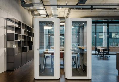 Office corridor featuring two white soundproof phone booths and a large bookshelf.