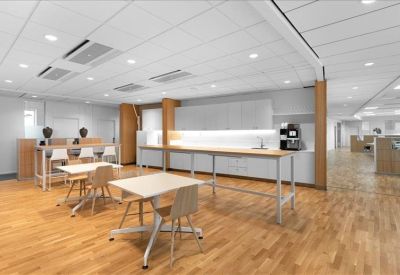 Bright communal kitchen and dining area with warm wood flooring and high tables.