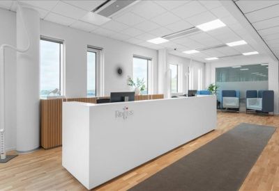 Minimalist white reception desk with wood flooring and lounge seating in the background.