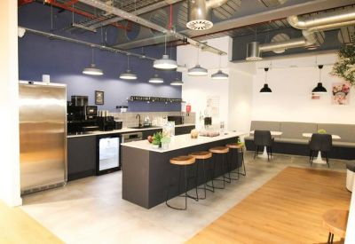 Sleek communal kitchen with a dark island and hanging industrial pendant lights.