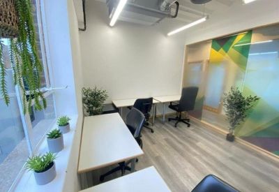 Bright private office suite with white desks and vibrant wall art.