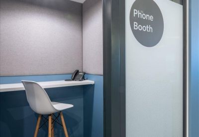 Private phone booth area with a high stool and desk for quiet calls.