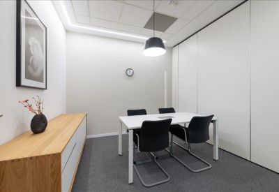 Minimalist meeting room with a white table, black chairs, and a wooden sideboard.