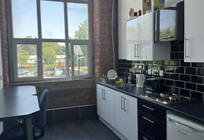 Modern kitchenette with white cabinets, black tiled backsplash, and large window.