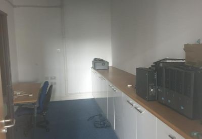 Compact office storage room with white cabinetry and blue carpeting.