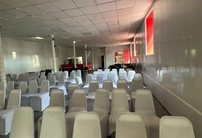 Large event space set up with rows of white chairs for a presentation.