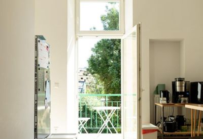 Bright sunlit breakroom with white walls, a wooden bench, and balcony access.