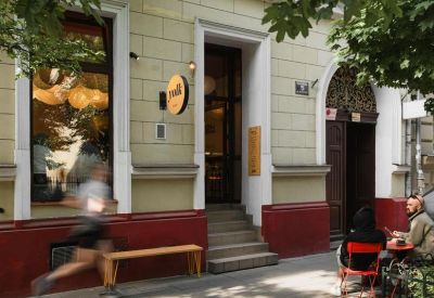 Exterior entrance of the Józefa Sarego 5, 31-047 Kraków, Poland building with a red facade and sidewalk bench.