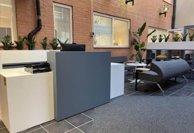 Modern grey reception desk in a brightly lit lobby area with brick walls.