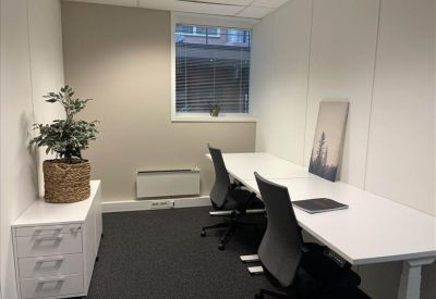 Private two-person office with white desks and a potted plant.