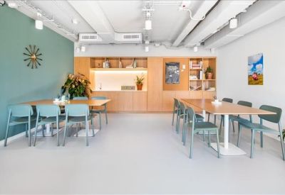 Bright communal dining area with light wood tables and a teal feature wall.