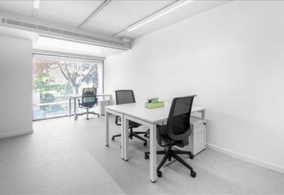 Private office suite with white desks and large windows overlooking trees.