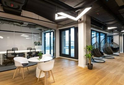 Lounge area with white cafe tables and black hanging wicker egg chairs.