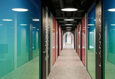 A long hallway with blue and pink glass partitions and circular ceiling lights.