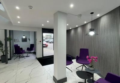 Contemporary waiting area with purple chairs and a marble-effect floor.