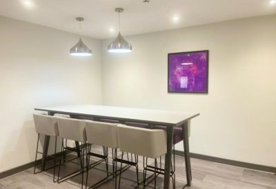 High-top communal table with light grey stools under silver pendant lighting.