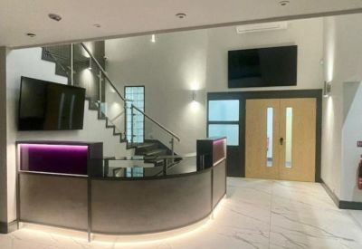 Branded reception area with a curved desk, purple backlighting, and a modern staircase.