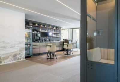 Communal break area with a kitchen, dining tables, and a large scenic wall mural.