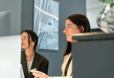 Close-up of two professional women working at a desk in a modern office.