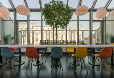 Bright dining area with colorful chairs and a glass roof.