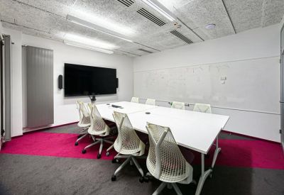 Minimalist conference room with a long white table and pink carpet accents.