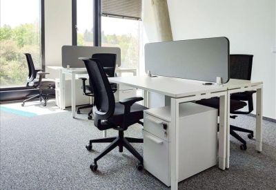 Bright open-plan office with white desks and ergonomic black mesh chairs.