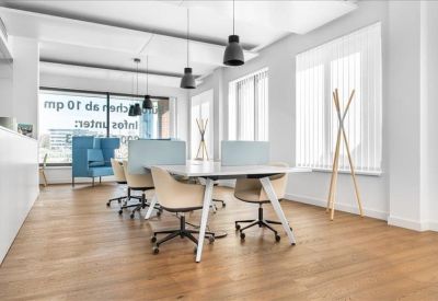 Spacious communal workspace with wooden flooring and modern pendant lighting.