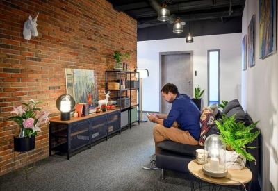 Lounge area with a brick feature wall, unicorn bust, and person sitting on a sofa.