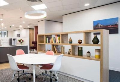 Communal break area with a round table, colorful chairs, and a decorative wooden bookshelf.
