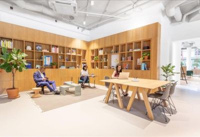 Lounge area with wooden bookshelves, a potted plant, and a large communal table.