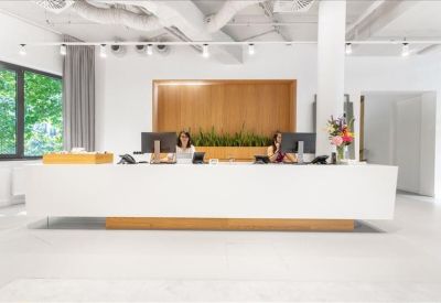 Reception area featuring a long white minimalist desk and light wood wall panelling.