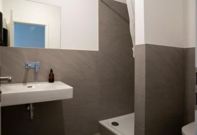 Clean, modern bathroom with gray tiling, white sink, and walk-in shower.