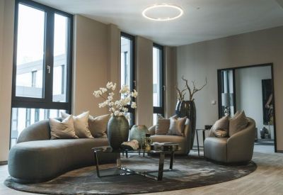 Stylish lounge area with curved grey sofas and large floor-to-ceiling windows.