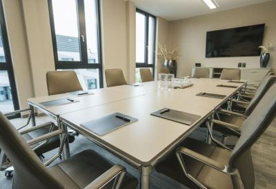 Long white boardroom table with grey leather chairs and built-in technology.