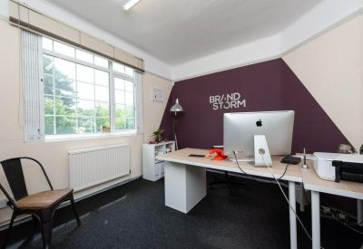 Bright private office featuring a purple accent wall with branding and a white desk.