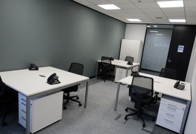 Four-person office space with grouped white desks and matching storage units.