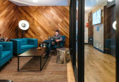Cozy breakout area with wood-paneled walls, teal armchairs, and a low coffee table.