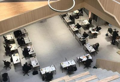 High-angle view of a large open-plan workspace with desks arranged in a U-shape.